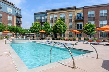 A swimming pool surrounded by orange umbrellas and lounge chairs.